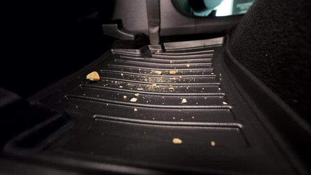 Garbage and dirt in the car. Cookie crumbs fall on the car mat in the car. Garbage in the car interior.