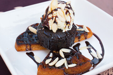 Delicious Chocolate Belgian Waffle with cup cake or muffin, Vanilla ice cream, chopped almond and chocolate sauce in white plate on table.
