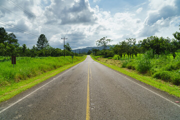Fototapeta na wymiar Lonely road in Costa Rica with grassy sidewalks