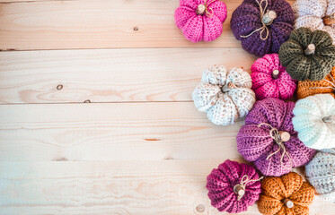 colorful handmade crochet pumpkins on light wooden ground with space for text