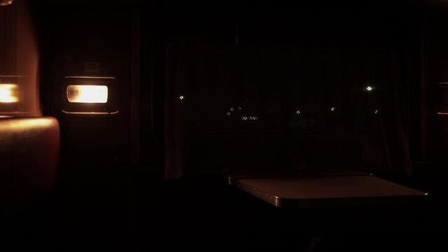 Inside compartment of corridor coach of railway passenger train at night. Light from luminaire is lit inside carriage. City lapms outside window. Empty russian railroad wagon. Travel tourism. Nobody