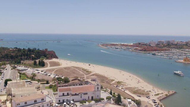 Aerial drone view of Arade River mouth, Portimao city and recreational boat Marina in the background,  at Algarve tourism destination region, Portugal.