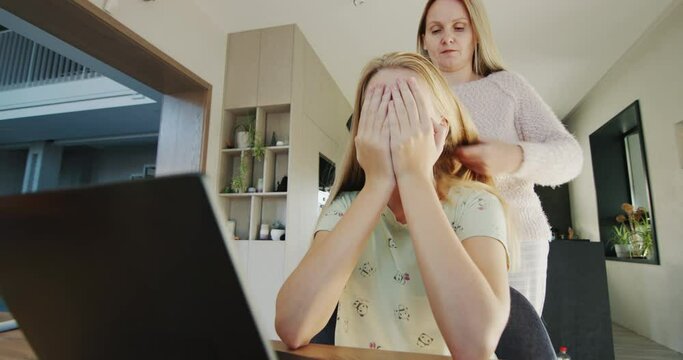 Woman trying to untangle her teenage daughter's long hair