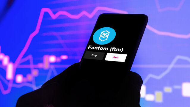 An investor's analyzing the fantom $ftm coin on screen. A phone shows the crypto's prices to invest in FTM.
