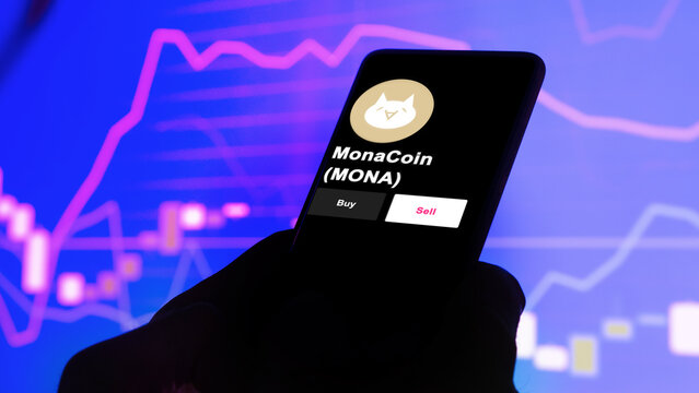 September 13th 2022, London UK. An investor's analyzing the MonaCoin (MONA) coin on screen. A phone shows the crypto's prices to invest