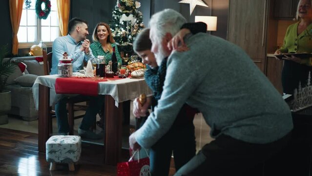 Granddaughter runs to hug grandfather who is visiting family on a Christmas