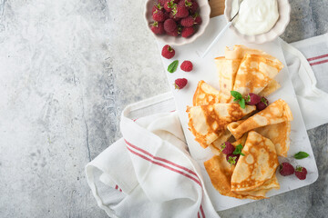 Pancakes. Stack of crepes or thin pancakes with berries, with raspberries and honey for breakfast. Homemade breakfast. Copy space. Selective focus.