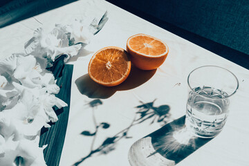 Glass of water with oranges and flowers