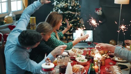 Happy family on Christmas lunch greeting their family and friends using a video call - Powered by Adobe