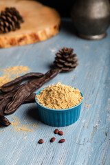 Carob pods and carob powder over a blue wooden background.