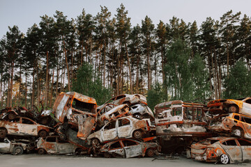 Fototapeta premium A pile of rusty burnt cars in Irpen in April 2022, shot at by Russian troops. A cemetery of wrecked cars of civilians trying to evacuate from the war zone.