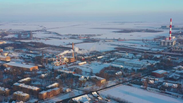 Above view on industrial complex, smoke form chimneys of district heating plant, pollution, roofs of houses white of snow, frosty settlement, cityscape in the wintertime.  