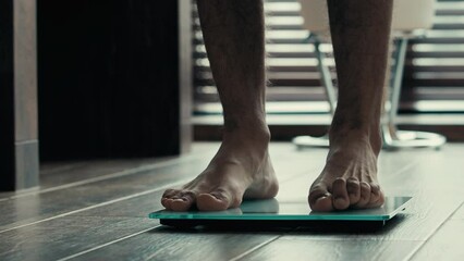 Close-up male legs foots stand on electronic digital scales unknown man sportsman athlete check weight loss control unrecognizable guy checking results exercise in gym counts calories obesity anorexia