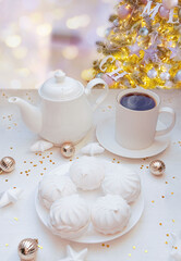   Winter, Christmas, New Year decorations composition, concept, background. White Mug, cup of tea, coffee, steam, meringue on Christmas Tree background. Christmas greeting card. Interior design.