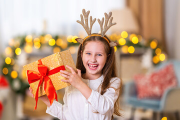 sweet, cheerful, mischievous little girl with deer horns, with box in her hands, tied with red...
