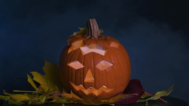 Festive pumpkin for Halloween in the form of a jack-o'-lantern, in autumn leaves