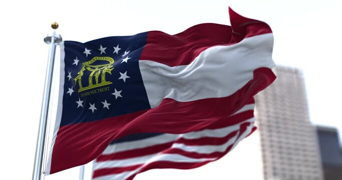the flag of the US state of Georgia waving in the wind with the American stars and stripes flag blurred in the background