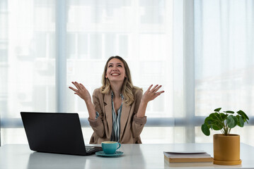 Young happy business woman sitting in her office at work and is happy because she hear her favorite...