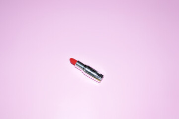 compact red lipstick in a shiny case on a pink background
