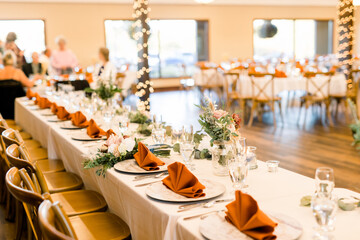 Autumn/fall wedding reception with orange napkins and rustic table settings