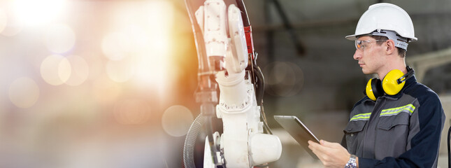 Portrait of male engineer worker using digital tablet for control automatic robotic arm machine in...