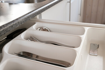 Drawer with cutlery, which contains knives, forks and spoons, in the kitchen. 