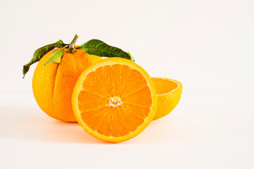 Orange with cut in half and green leaves isolated on white background.