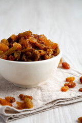 Organic Dried Raisins in a White Bowl, side view.