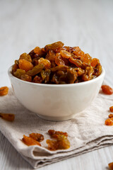 Organic Dried Raisins in a White Bowl, low angle view. Close-up.