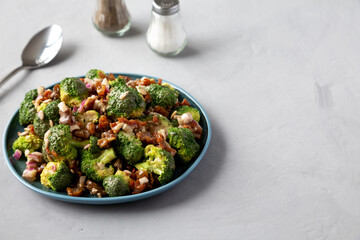 Homemade Broccoli Bacon Salad on a Plate on a gray background, side view. Space for text.
