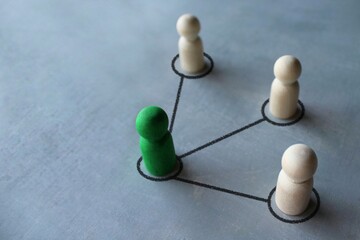 Green wooden doll connected with other wooden dolls. Communication social. Cooperation, collaboration. Project leadership personnel management concept