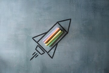 Sketch of rocket ship launch made with colorful chalk on chalkboard with copy space. Creative learning, imagination and back to school concept
