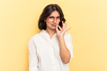 Young Indian woman isolated on yellow background with fingers on lips keeping a secret.