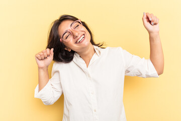 Young Indian woman isolated on yellow background celebrating a special day, jumps and raise arms with energy.