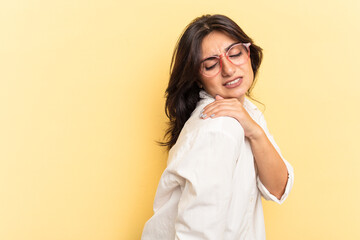 Young Indian woman isolated on yellow background having a shoulder pain.