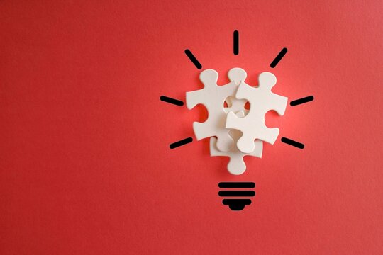 Lightbulb from puzzles on red background with copy space. Inspiration, creative idea concept.