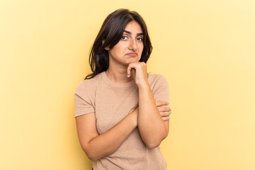 Young Indian woman isolated on yellow background thinking and looking up, being reflective,...