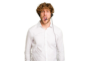 Telemarketer man working with a headset isolated on green chroma background screaming very angry and aggressive.