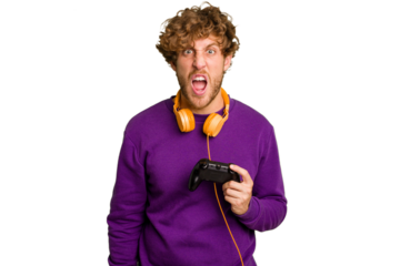 Young caucasian gamer man holding a game controller isolated on white background screaming very angry and aggressive.