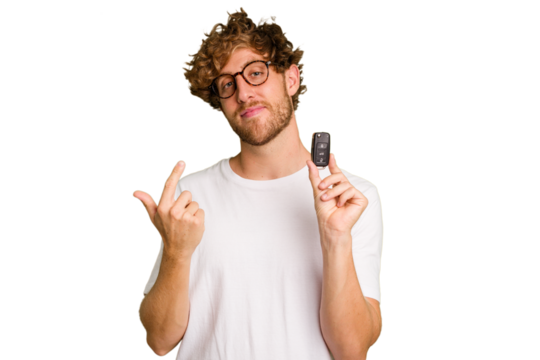 Young caucasian man holding car keys isolated on white background pointing with finger at you as if inviting come closer.