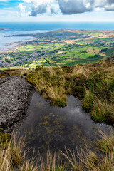 Puddle on the top of mouintain. Small village in background, Sea on the horizon. Vertical perspective.