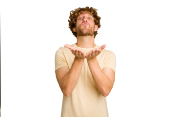 Young caucasian man isolated on green chroma background folding lips and holding palms to send air kiss.