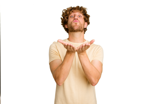 Young caucasian man isolated on green chroma background folding lips and holding palms to send air kiss.