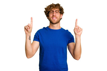 Young caucasian man isolated on green chroma background indicates with both fore fingers up showing...