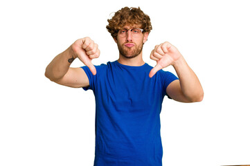 Young caucasian man isolated on green chroma background showing a dislike gesture, thumbs down....