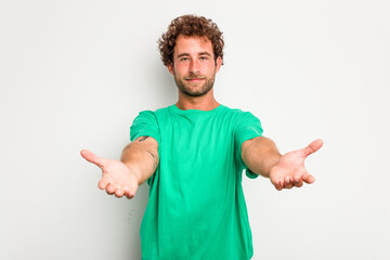 Young caucasian curly hair man isolated on white background showing a welcome expression.