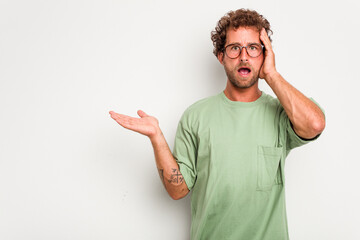 Fototapeta premium Young caucasian curly hair man isolated on white background impressed holding copy space on palm.