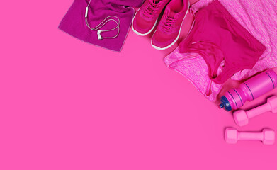 Fitness clothes and equipment laying on a pink background view from above