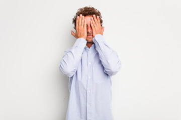 Young caucasian curly hair man isolated on white background having fun covering half of face with palm.