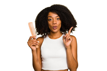 Young african american woman holding hair comb isolated having some great idea, concept of...